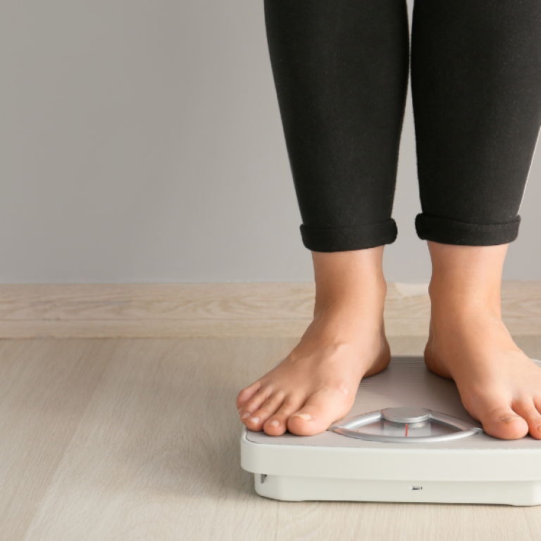 woman on scale after weight loss treatments in NoVA